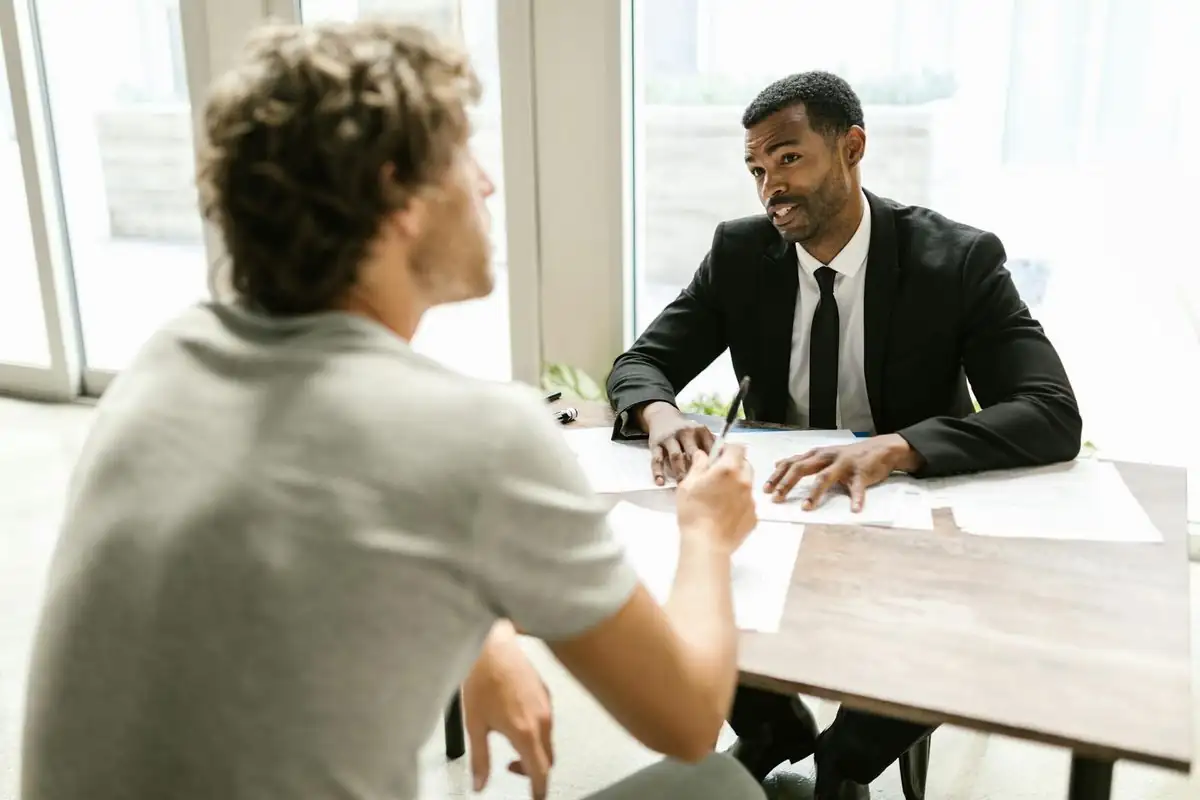 Một đại lý bảo hiểm trao đổi với khách hàng qua giấy tờ trong buổi tư vấn.