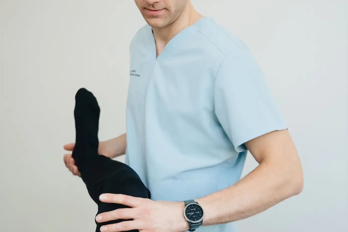 Chuyên viên trị liệu tập chân cho một người nằm trên giường trị liệu